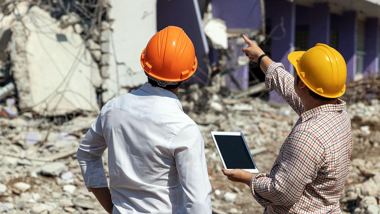 Two workers inspecting fallen debris