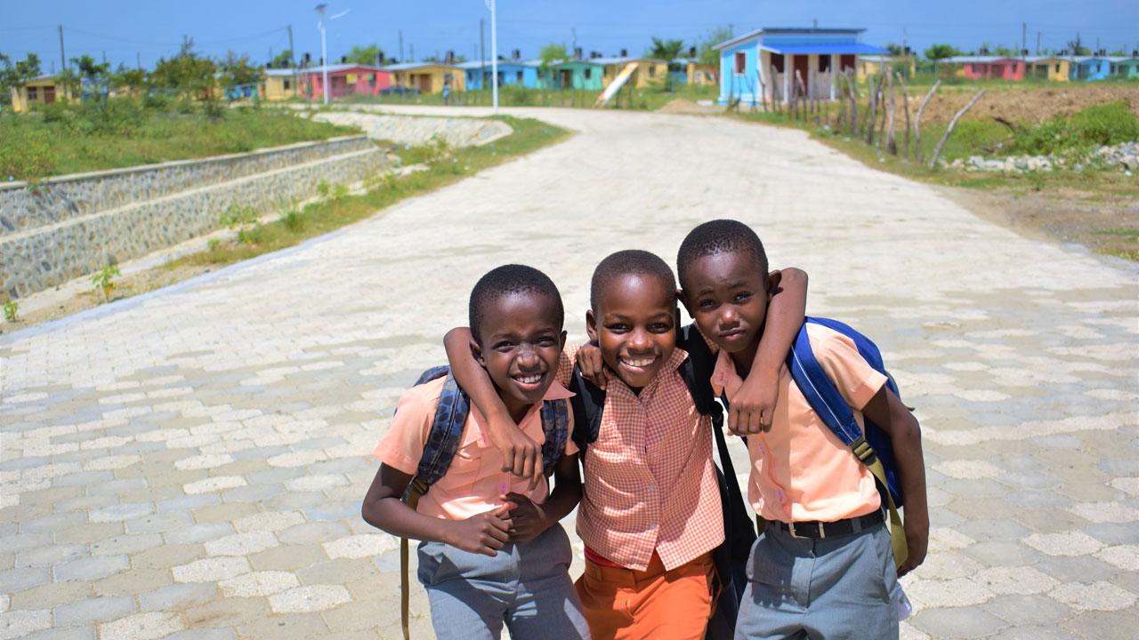 Three young boys stand in front of new housing development in Haiti